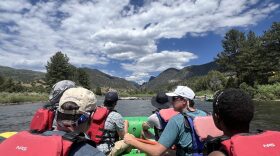 A group of men ride on a raft along a long stretch of water.