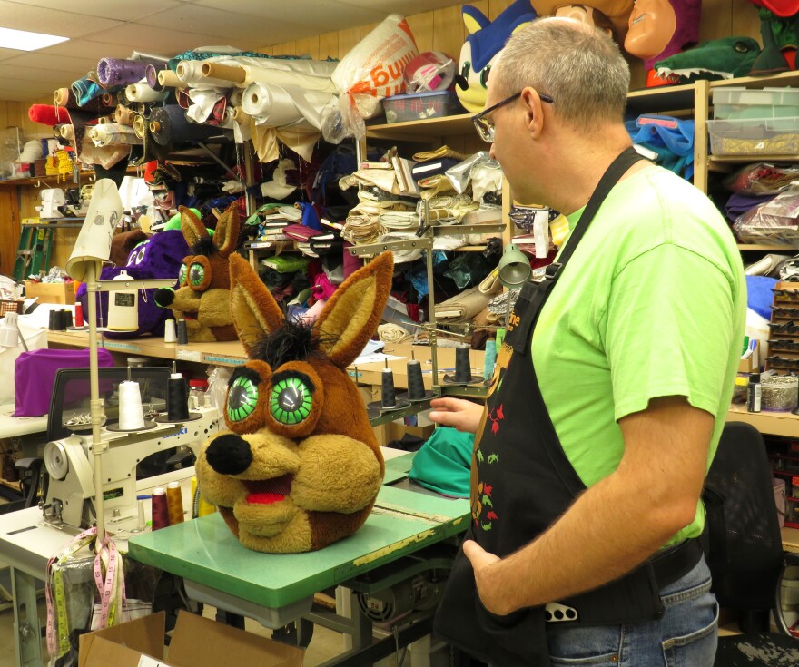 Starline Costume shop owner Jacob Dell poses next to The Spurs Coyote head while they refresh the mascots look.