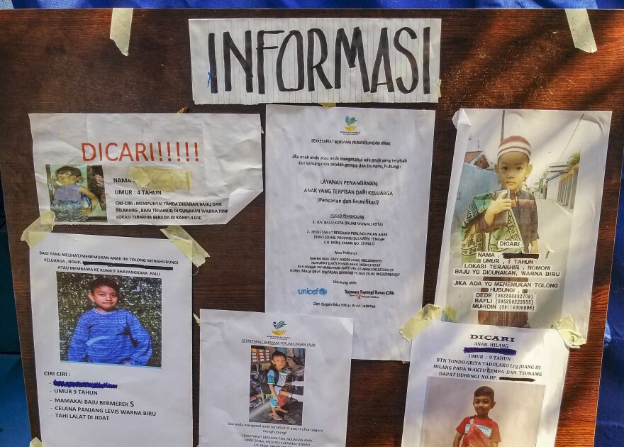 Photos of missing children are displayed on a bulletin board at an encampment in Palu run by Save the Children and UNICEF.