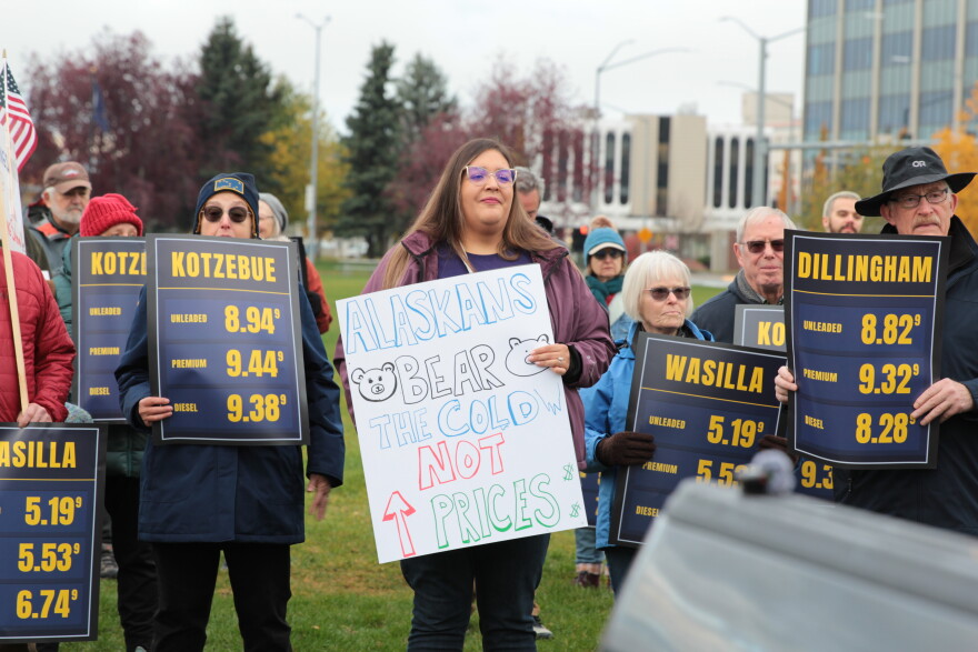 Ana Rodriguez, a member of Alaska's caregiver union, brought a homemade sign to a rally opposing President Trump's visit. It read: "Alaskans bear the cold, not prices." Other protesters held signs showing gas prices in various Alaska communities.