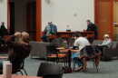 Students sit by themselves at separate tables and couches in a lounge area.