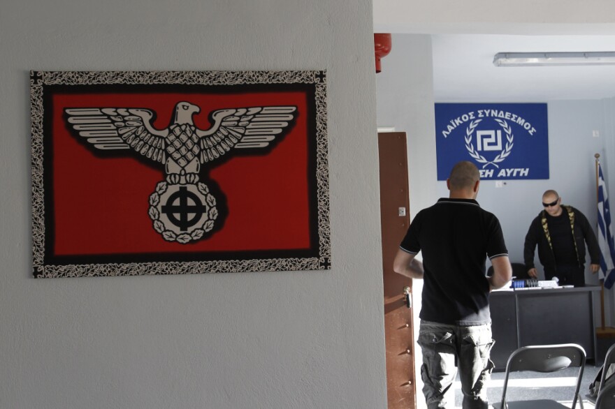 A Nazi-style poster with a Celtic cross replacing the swastika is displayed on the wall as Golden Dawn candidate Giorgos Germanis (right) and an unidentified man are seen at a party office in the suburban town of Artemis, east of Athens.