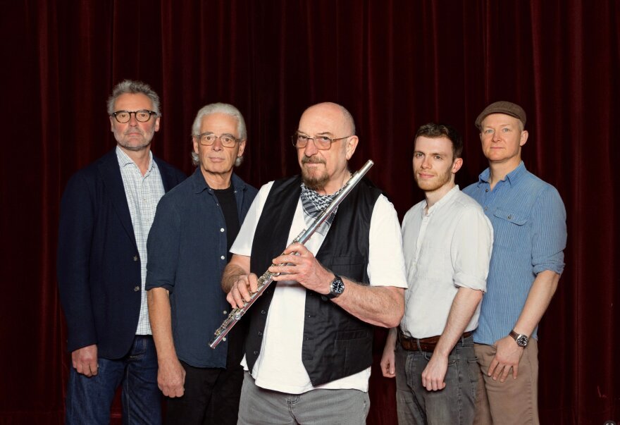 Ian Anderson holds a flute while posing with his band.