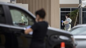 A health worker screens a driver at a drive-thru COVID-19 testing site in South Austin.