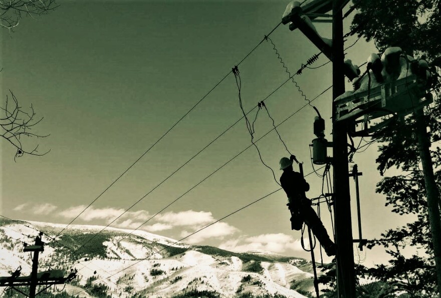 A Holy Cross line worker high on a pole with a snowy backdrop. The rural energy co-op's rates are going up, but not much -- especially compared to for-profit utilities like Xcel. State legislators have started a new commission to investigate rate hikes around Colorado.