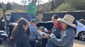 Jorge Sanchez onto of the black truck offloads food, supplies and jackets to the farmworkers at Propagations Farms in Half Moon Bay. 