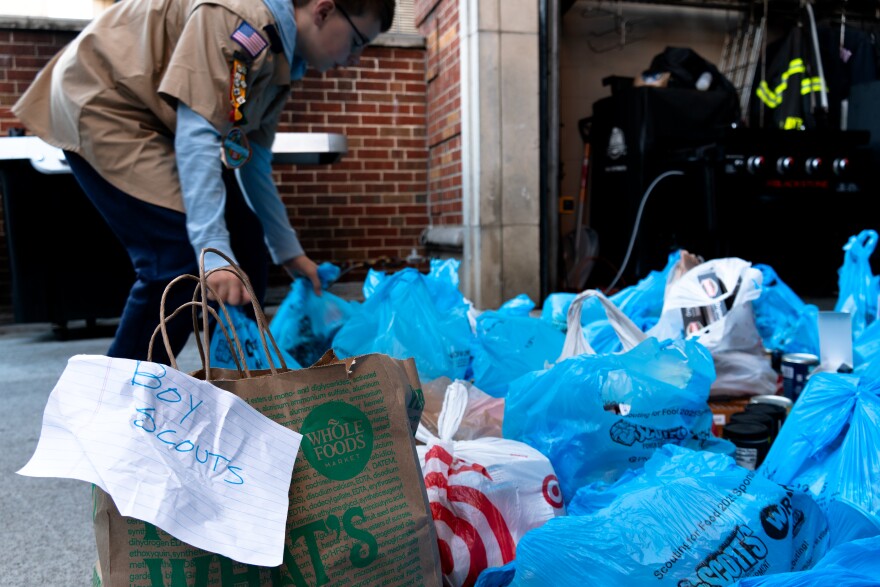 Grocery bags of non-perishable food items and canned goods sit outside on the ground of the fire station in Clayton, Mo.