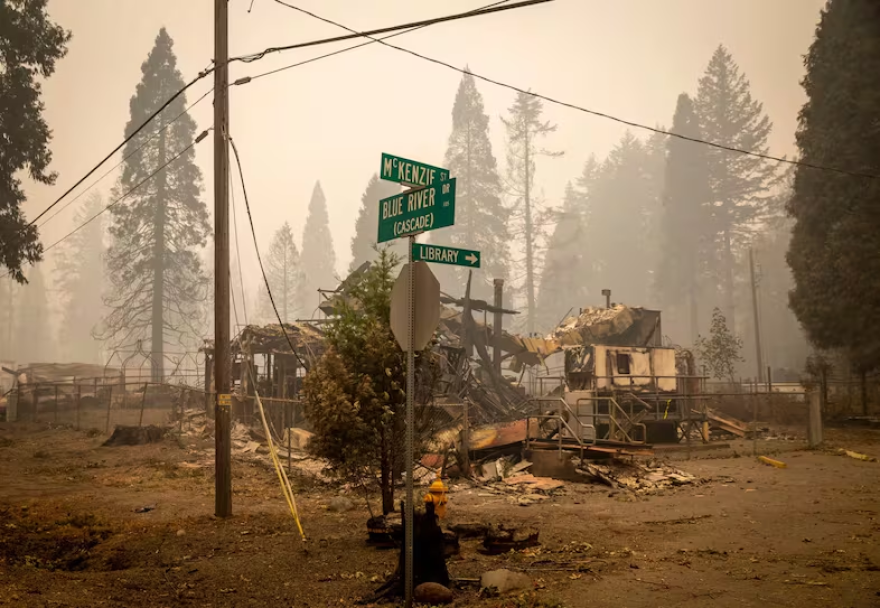 Street signs stand in front of buildings destroyed by fire.