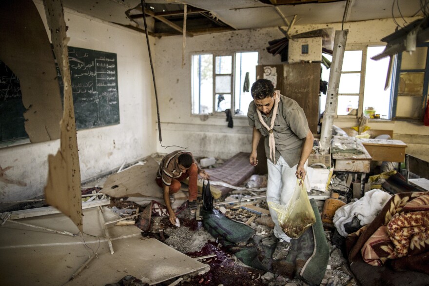 Palestinians collect human remains from a classroom inside Jabaliya school after it was hit by shelling on July 30, 2014.