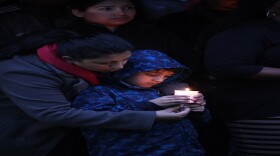 Nepal native Charu Simmons helps her 6-year-old son hold a candle for victims of Nepal's earthquake during a vigil this week at Southern Arkansas University.