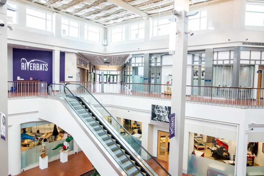 An escalator in the middle of the ACC Highland campus. A wall Says "Riverbats."