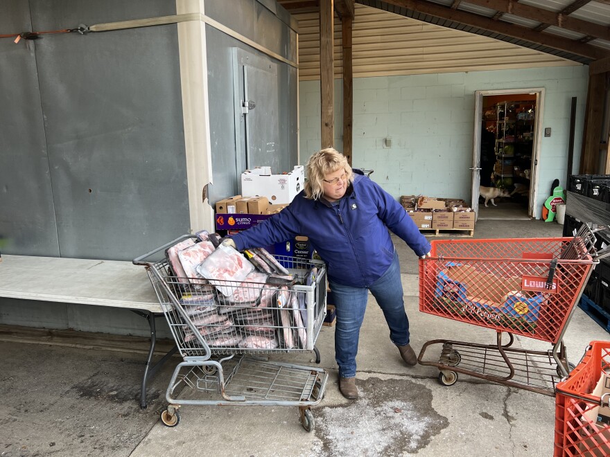 A volunteer puts meat inside a retired shopping cart, in preparation for Brookside Church's weekly food pantry.
