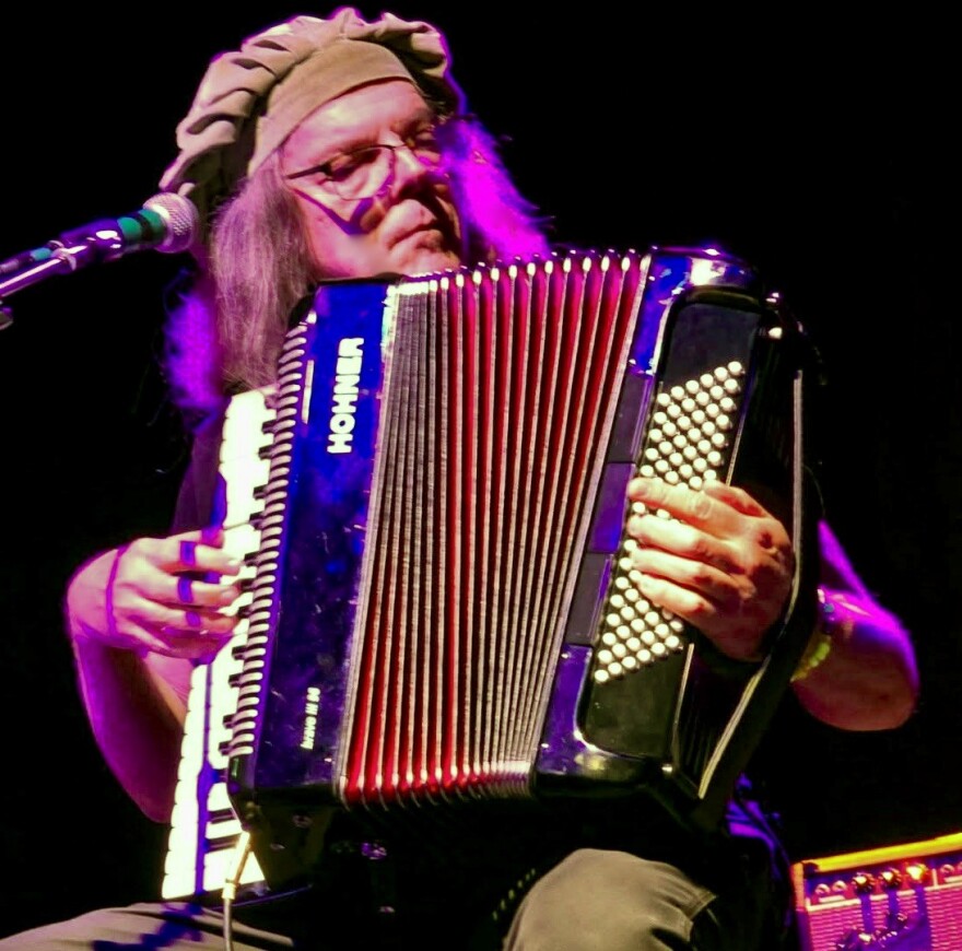 A man sitting playing an accordion. 