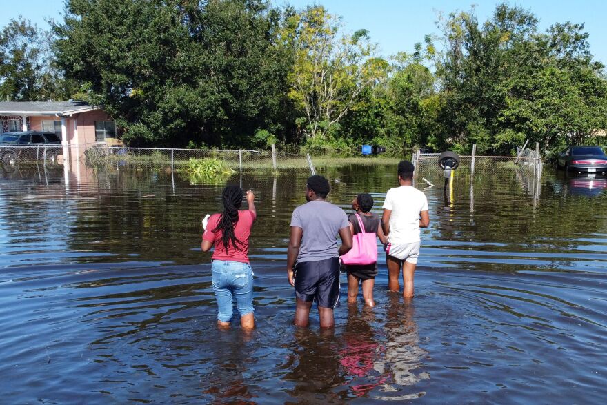 Residents wade through water to get to their house in a flooded neighborhood on Oct. 1, 2022 in Orlando, Fla.