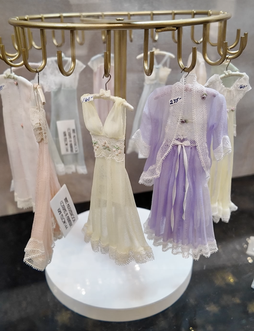 Sheer and lacy gowns, hanging from a brass circular display stand. The clothing is one-twelfth scale, though it may not be obvious looking at the photo.