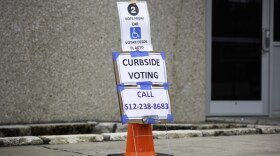 a sign that says "curbside voting" and lists a phone number to call.