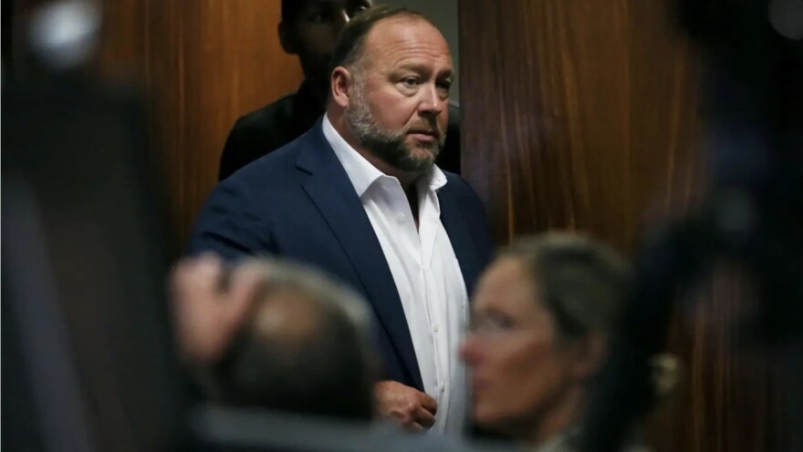 Alex Jones walks into the courtroom in front of Scarlett Lewis and Neil Heslin, the parents of 6-year-old Sandy Hook shooting victim Jesse Lewis, at the Travis County Courthouse in Austin in 2022.