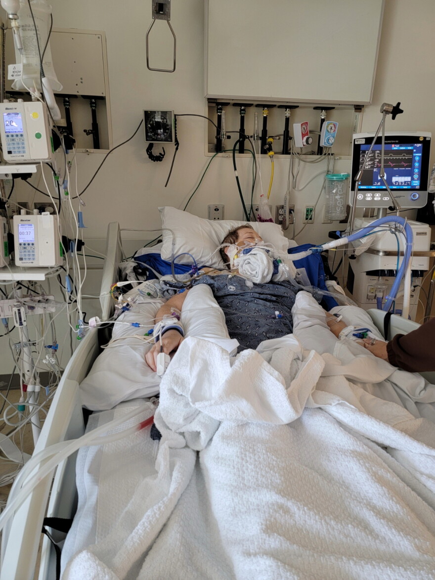 Jennifer George lays in a hospital bed and is connected to different medical devices.