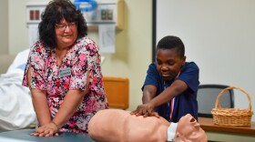 Lori Drozdis explains chest compressions to Medwin Enzo Kamdem Kamwa as "Stayin' Alive" plays in the background.