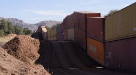 A long row of double-stacked shipping contrainers provide a new wall between the United States and Mexico in the remote section area of San Rafael Valley, Ariz., Thursday, Dec. 8, 2022. Work crews are steadily erecting hundreds of double-stacked shipping containers along the rugged east end of Arizona’s boundary with Mexico as Republican Gov. Doug Ducey makes a bold show of border enforcement even as he prepares to step aside next month for Democratic Governor-elect Katie Hobbs.