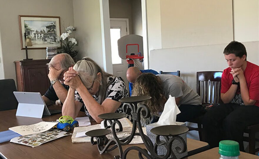 Worshipers bow their heads in prayer on a Sunday morning at Brody and Liz Olson's home, which functions as a space for religious gatherings while he works on establishing a church in the community.