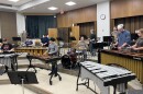 A group of people playing on xylophones, marimbas, and drum kits.