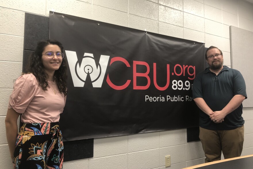 Tri-County Regional Planning Commission senior planners Reema Abi-Akar, left, and Michael Bruner stand next to the WCBU banner in the station's newsroom.