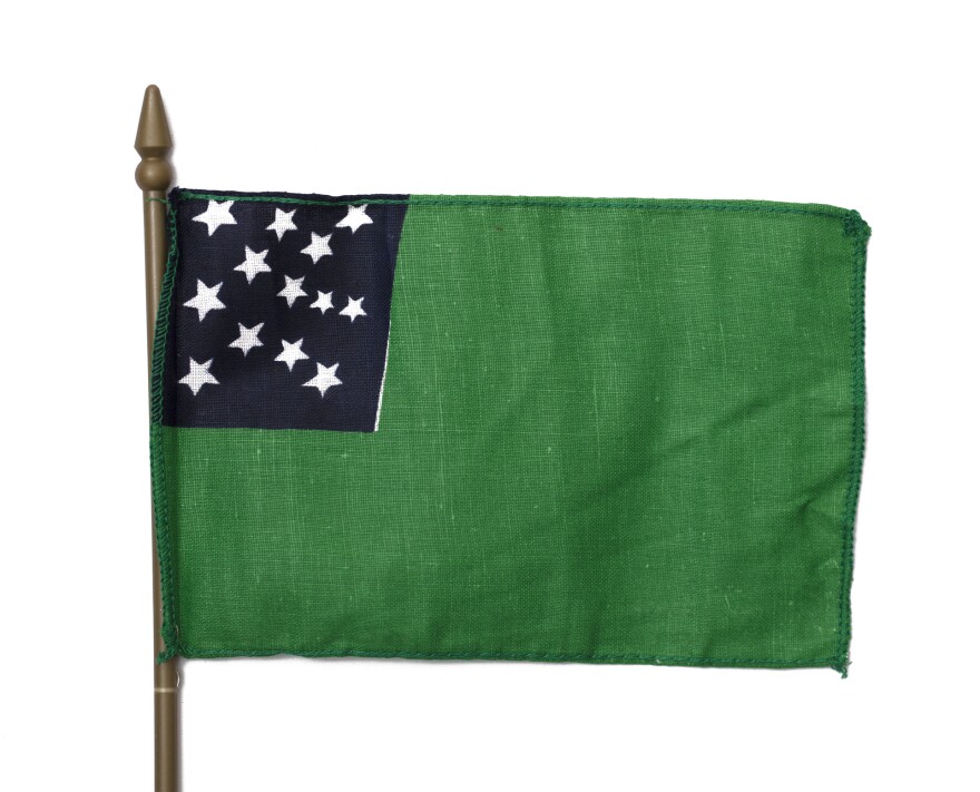 a flag with a green blackground and a blue square in the upper left-hand corner with white stars inside