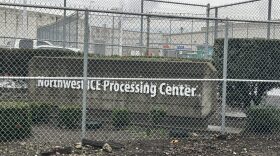 A concrete sign that says "Northwest Ice Processing Center" surrounded by barbwire