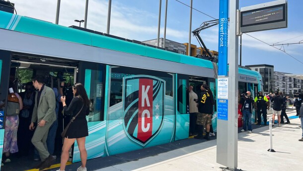 People board a streetcar with a KC Current-branded wrap