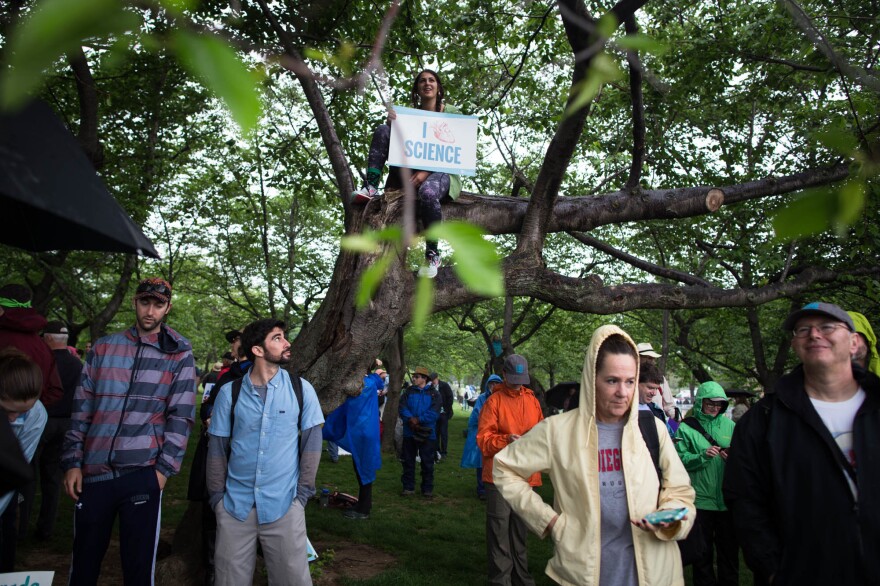 Participants seek cover from the rain to watch the rally.