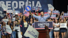 Sen. Jon Ossoff and former Atlanta Mayor Keisha Lance Bottoms take the stage together at the Georgia Theater. Behind them a crowd of young voters cheer with signs that say United for Georgia.