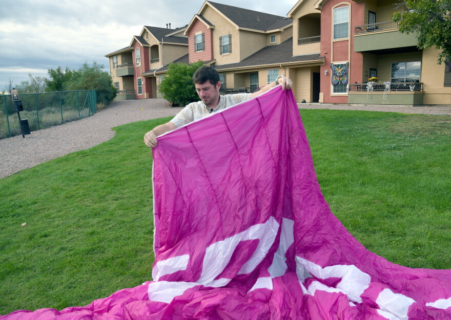 Jake Hutzler, holds his pink paramotor wing outside his home.