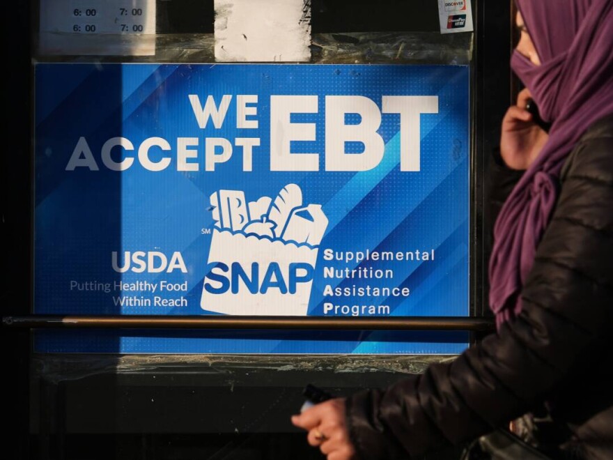 A SNAP EBT information sign is displayed at a bakery as a woman walks past in Chicago, Nov. 2.