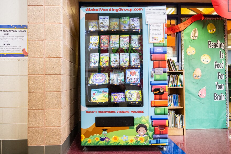 A light blue vending machine with books inside it