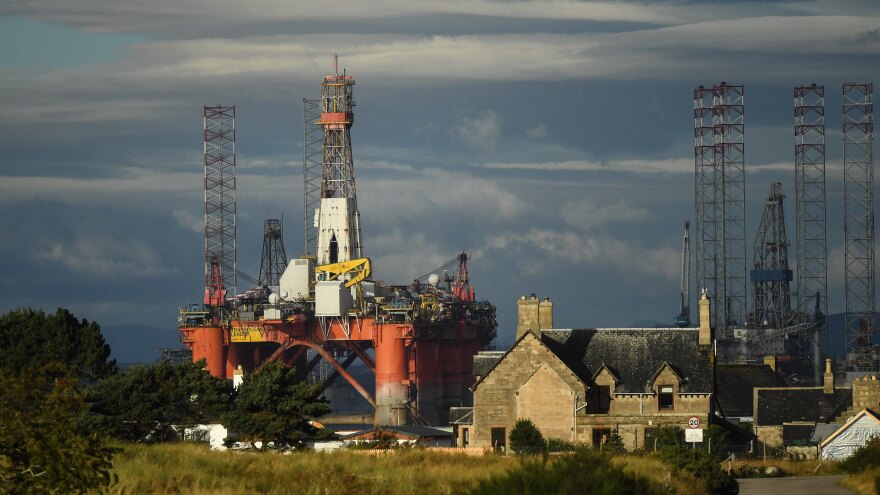 An oil rig towers over houses last week in Nigg, Scotland. Major players in the oil industry expect depressed oil demand and low prices to continue well into next year.
