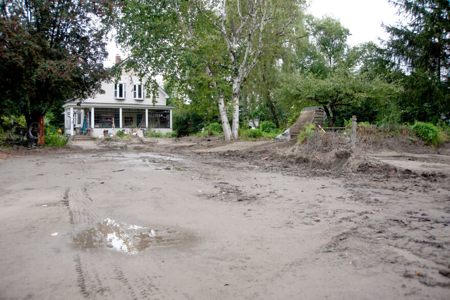 A muddy road leading to a home with a large porch