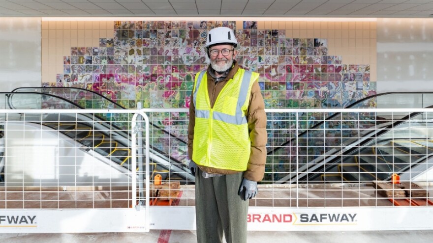 Artist Jerry Gretzinger stand in front of his artpiece, "Jerry's Map"