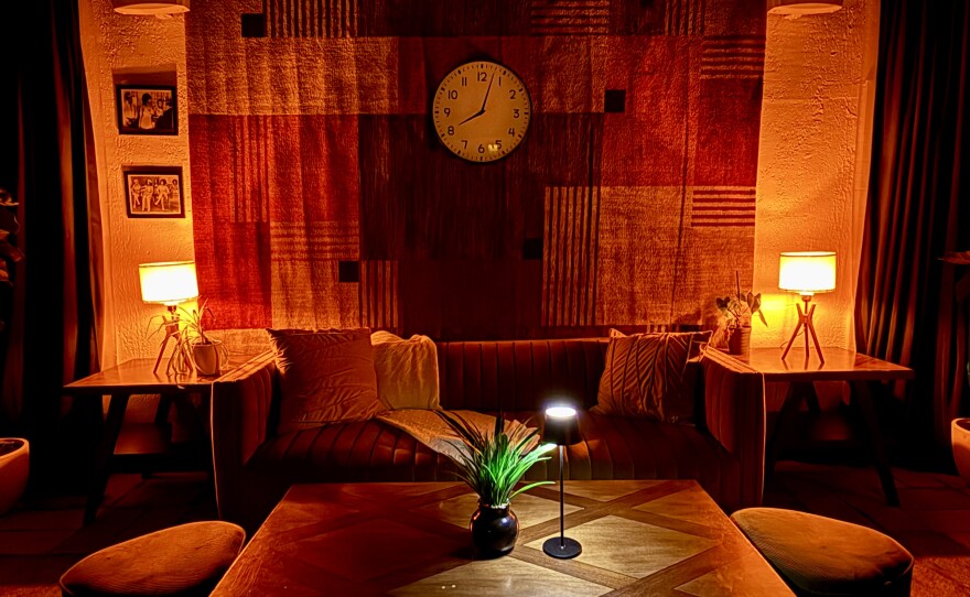 The open area at Off The Clock in Lake Worth Beach looks and feels like a living room, with its wide, pillow-filled couch at the center, surrounded by accent tables.