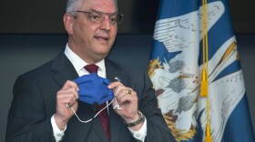 Louisiana Gov. John Bel Edwards holds up his own mask, taken off while he was speaking, to remind Louisiana residents that a highly effective thing within their power to do to prevent the spread of COVID-19 is to wear a mask. (Travis Spradling/The Advocate via AP, Pool)