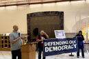 Harry Dunn is standing behind a podium, speaking to supporters about Jan.6