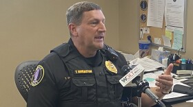 Police officer sits at his desk speaking into a microphone
