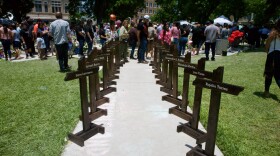  Wood crosses line a sidewalk leading to the makeshift memorial for the victims of the school shooting in Uvalde. People from all over the state have visited the small town to honor the victims of last week's deadly event.