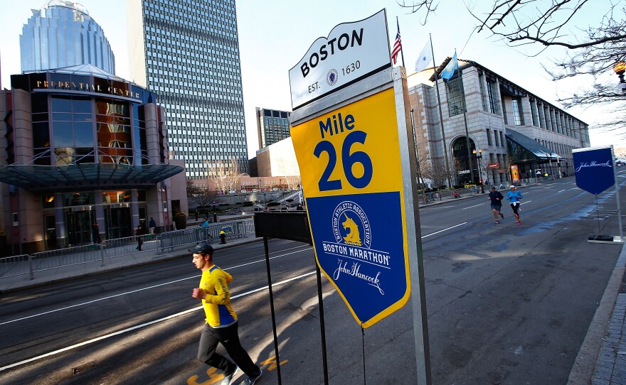 A few people run along Boylston Street near the 26-mile marker prior to the start of the marathon.