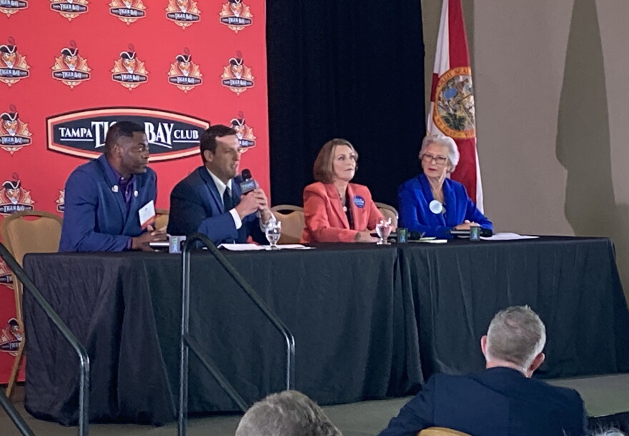 Four people sitting at a dais on a stage