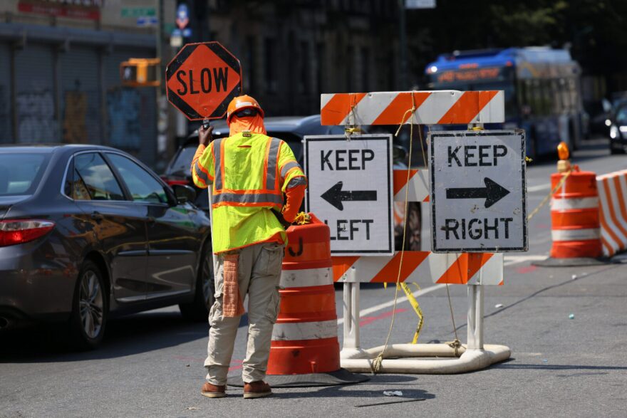 A Construction worker lowers their head as they direct traffic on a construction site in New York City.