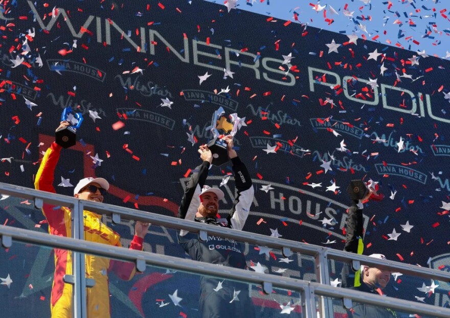Chip Ganassi Racing driver Alex Palou, left, Andretti Global driver Kyle Kirkwood, center, and Andretti Global driver Will Power raise their trophies after the Java House Grand Prix of Arlington on March 15.