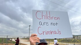 Protster holds a sign in front of the Dilley Detention Center on Saturday, April 18, 2026.