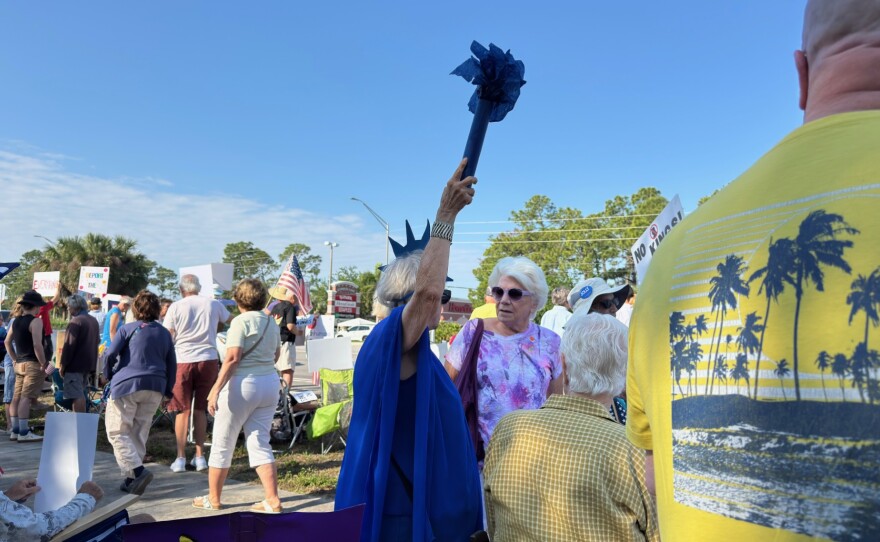 Protesters line U.S. 41 near Daniels Parkway on Saturday, March 28, 2026, for the No Kings rally.