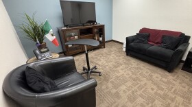 A room with a chair and a couch on opposite ends.